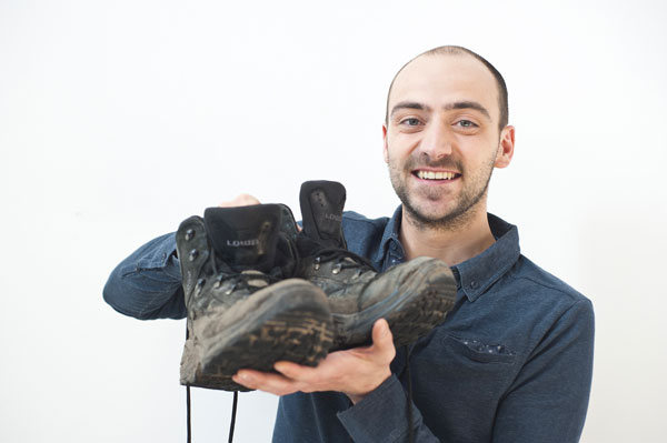 Jeune homme montrant une paire de chaussures de marche